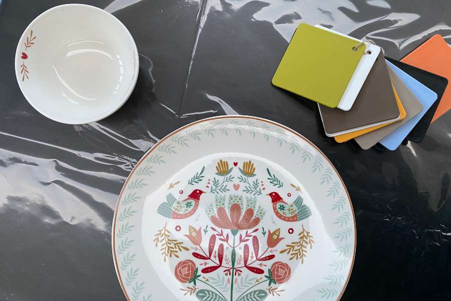 Una tavola ispirata alla natura: armonie di colore e stile Set di piatti decorati con motivi floreali e uccellini, accompagnati da campioni di colori per la tavola