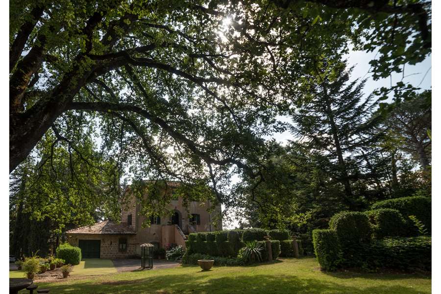 Antico Casale de La Trinità in estate – Foto di Fabio Fuser Vista dell’Antico Casale de La Trinità in una luminosa giornata estiva, incorniciato dai rami degli alberi