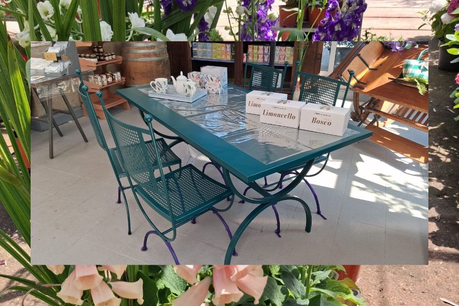 tavolo e sedie da esterno color verde petrolio esposti al garden de la trinità tra fioriture e complementi d'arredo per l'estate