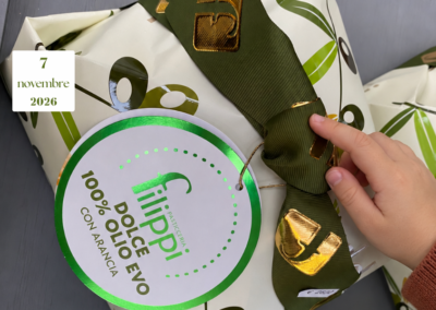 Una mano di bambino sfiora il fiocco verde di un dolce Filippi all’olio extravergine di oliva e arancia.