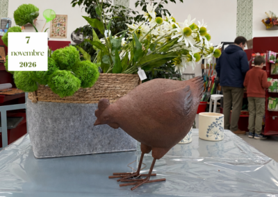 Fiori bianchi e verdi e una gallina decorativa in primo piano; un adulto e un bambino di spalle osservano un espositore nel garden