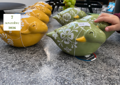 Una mano di bambino sfiora un uccellino verde in ceramica, accanto ad altri verdi e gialli con decorazioni floreali bianche